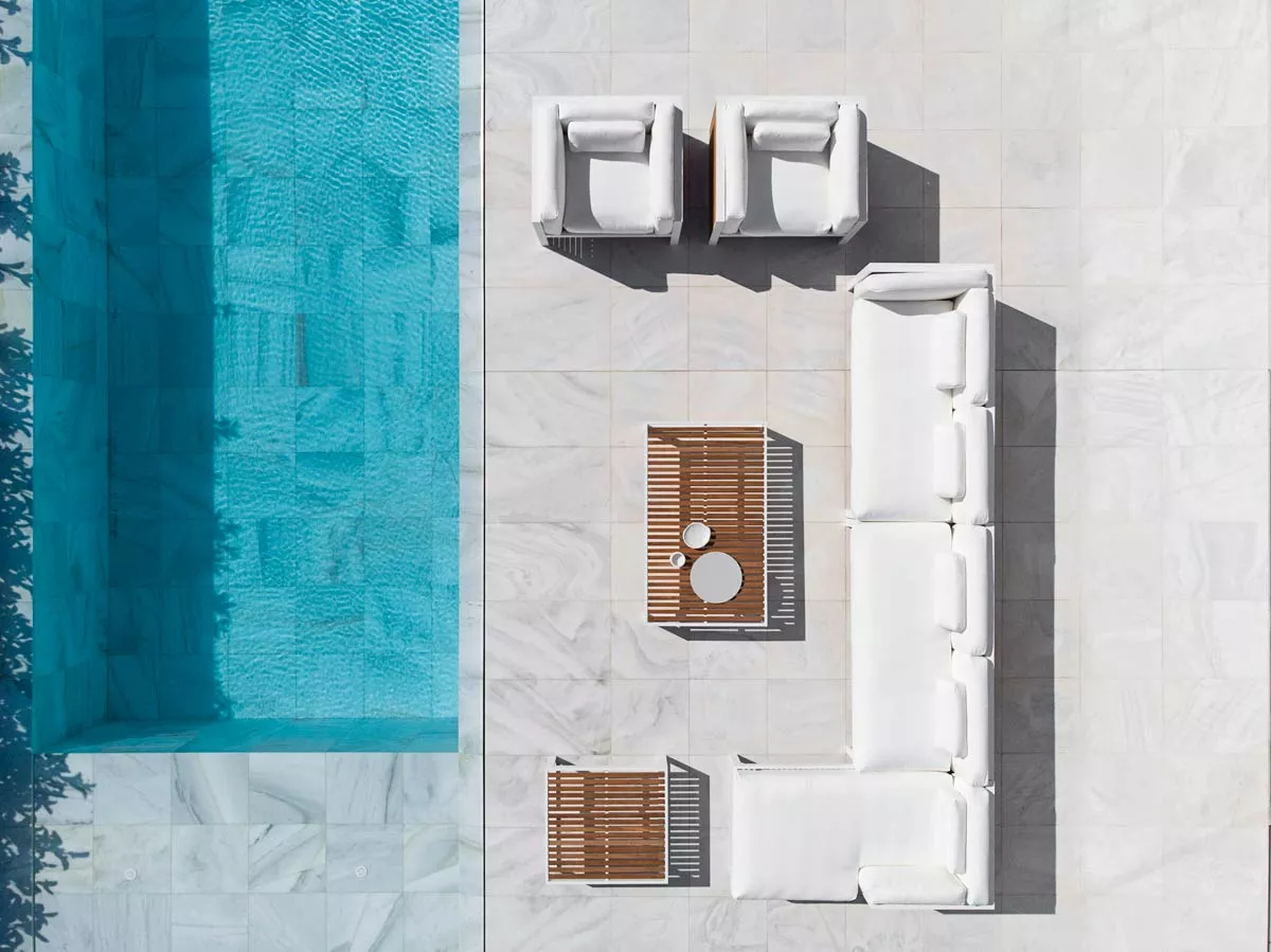 Gandia Blasco DNA Teakholz Gartenmöbel in Weiß, bestehend aus Sofas und Sesseln, auf einer hellen Steinfliese neben einem Pool.