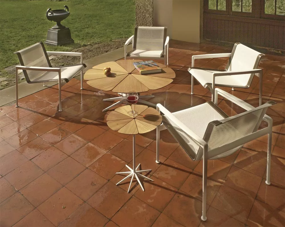 Knoll Studio 1966 Collection Lounge Sessel auf einer Terrasse mit runden Holztischen und einem Buch auf einem der Tische