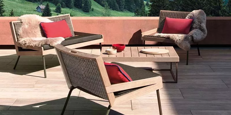 Outdoor-Loungegruppe von Ethimo Allaperto Mountain in Holzoptik mit roten Kissen auf einer Terrasse mit Bergblick.