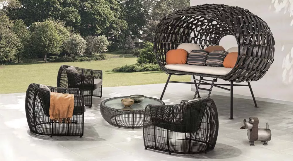 Kenneth Cobonpue Apollo Loungegruppe in Schwarz auf einer Terrasse mit Gartenblick, bestehend aus einem großen Sofa und drei Sesseln.