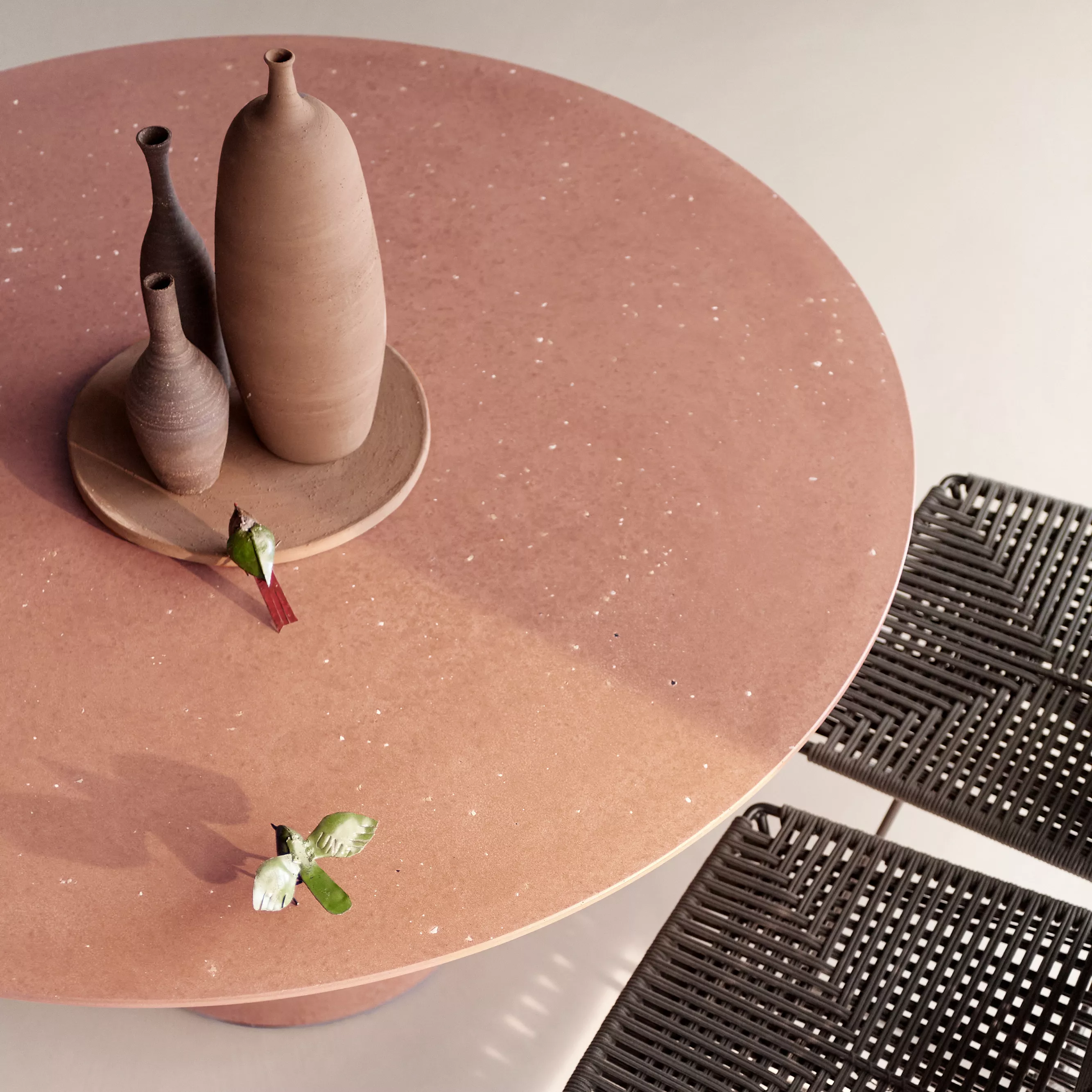 MDF Italia Rock Table in Terrakotta mit drei Keramikvasen und zwei geflochtenen Stühlen in einer stilvollen Wohnumgebung