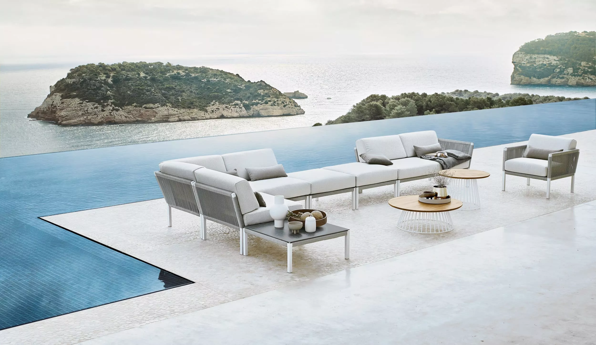 Solpuri Club A Lounge Möbel auf einer Terrasse mit Blick auf das Meer und Inseln im Hintergrund Mood Bild mit entspannter Atmosphäre