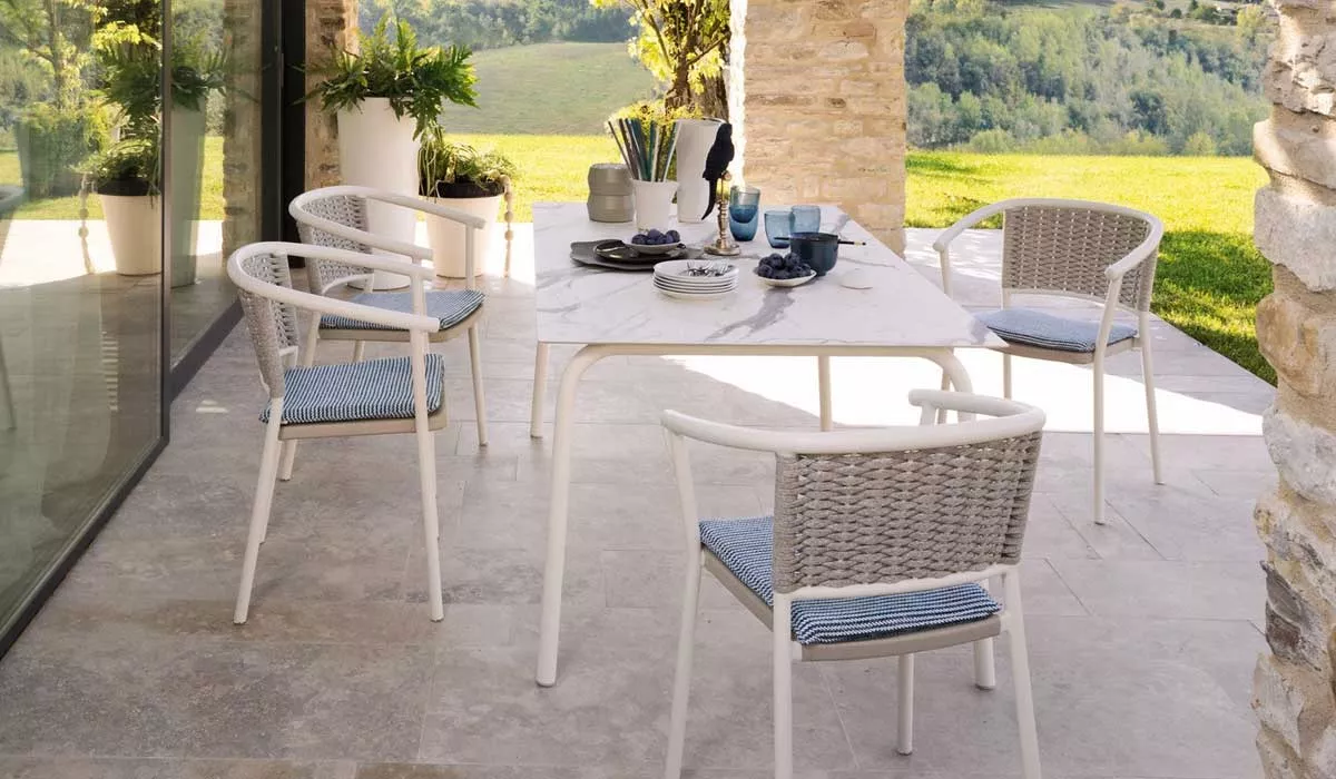 ALT: Roberti Lipari Essgruppe in Weiß auf einer Terrasse mit Blick auf einen grünen Garten, bestehend aus einem Tisch und vier Stühlen.