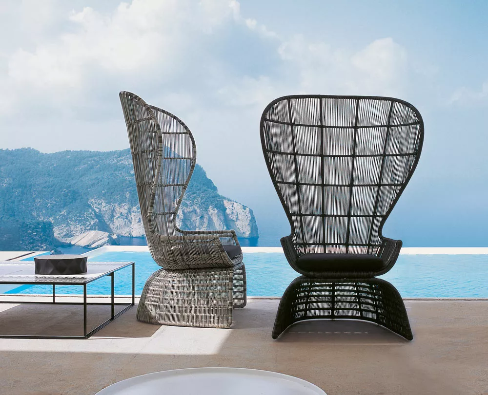 Zwei B&B Italia Crinoline Outdoor-Loungesessel stehen auf einer Terrasse mit Blick auf das Meer und die Berge im Hintergrund.