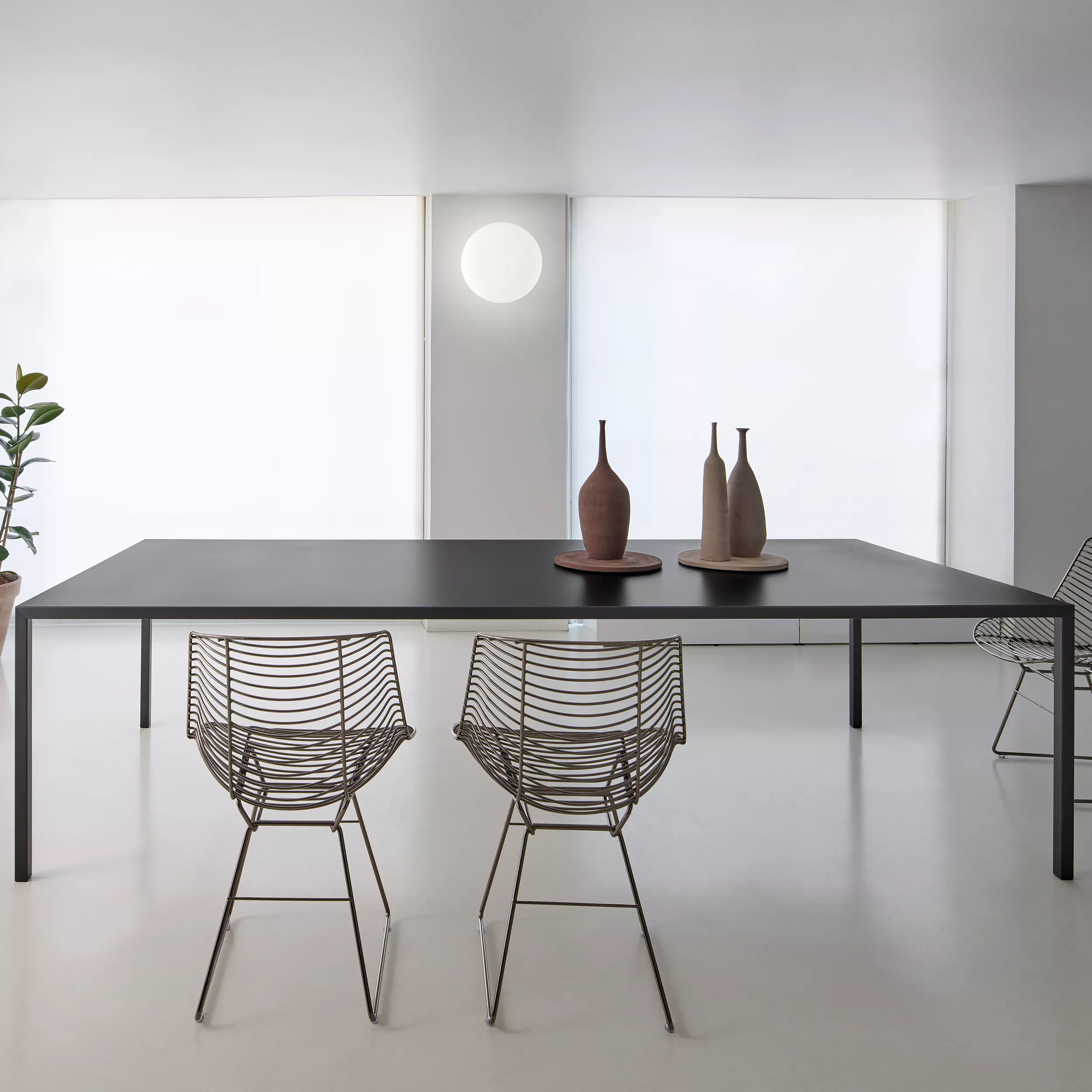 MDF Italia Tense Tisch 90x180 in einem modernen Raum mit zwei Drahtstühlen und dekorativen Vasen auf dem Tisch