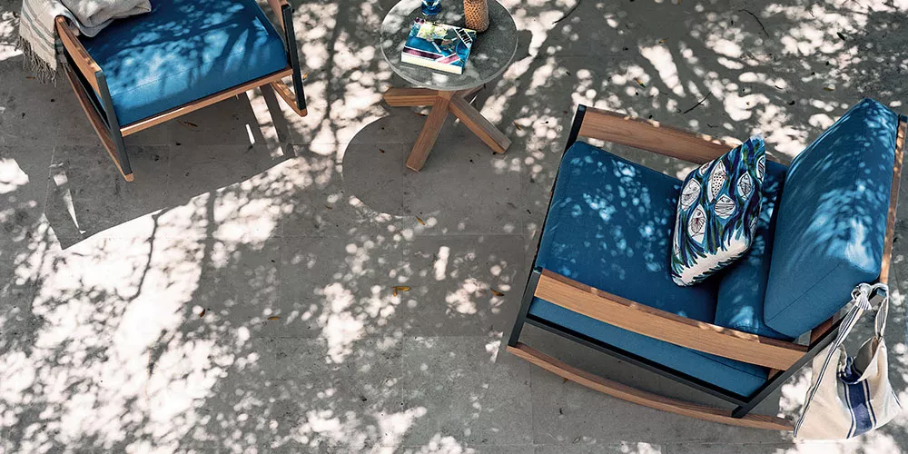 Roda Kollektion Nap, blauer Sessel mit Holzelementen, auf einer schattigen Terrasse mit Tisch und Kissen, Vogelperspektive.