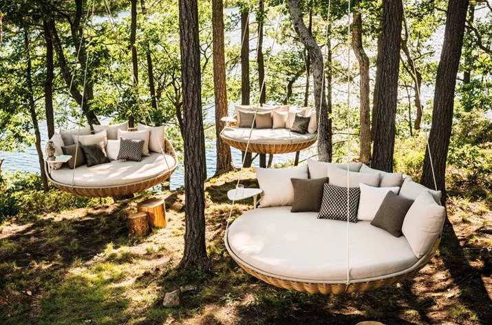 Drei Dedon Swingrest Hanging Lounger hängen im Wald über einem See und bieten eine gemütliche Sitzgelegenheit in der Natur