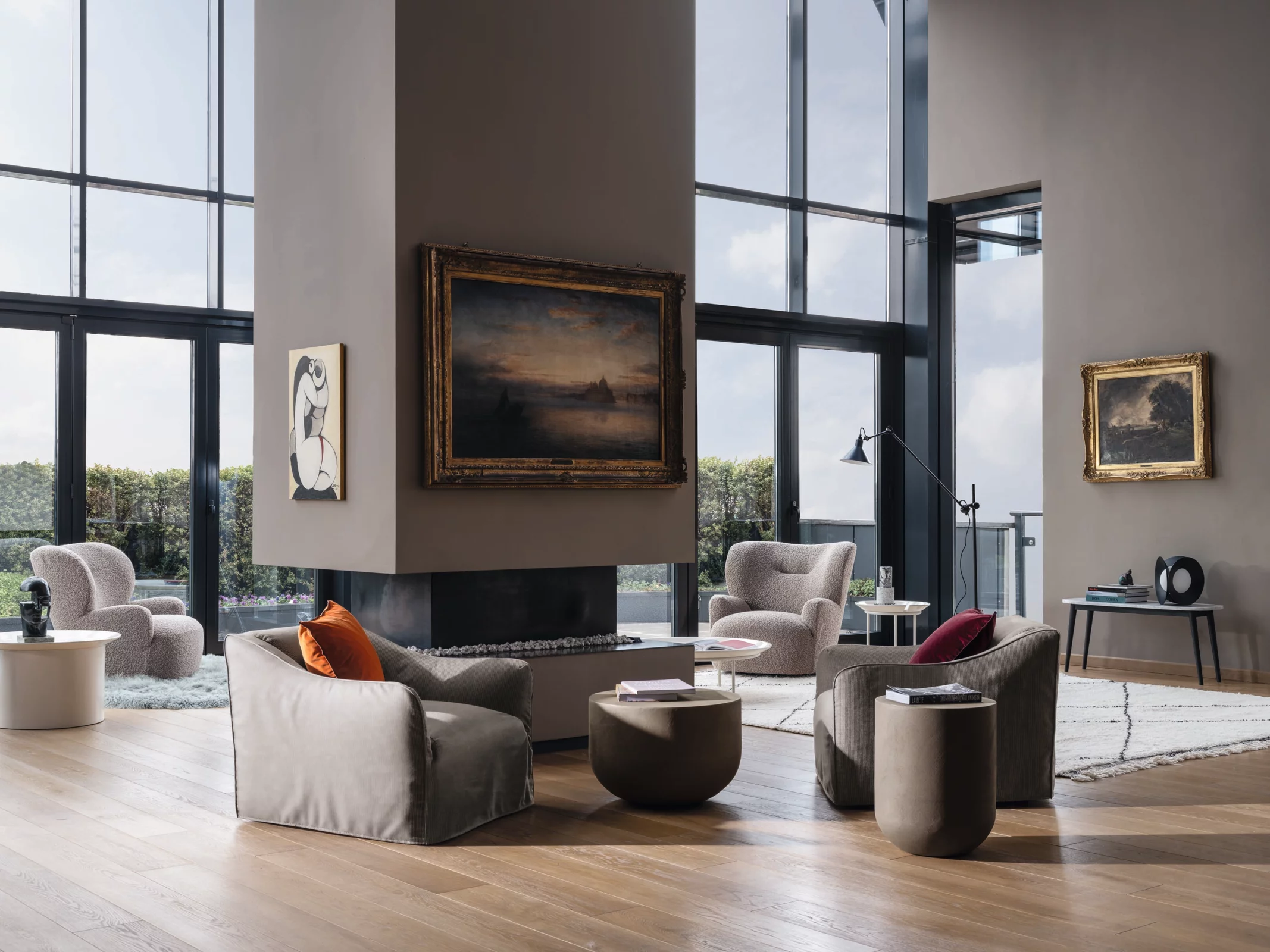 Ein stilvoll eingerichtetes Wohnzimmer mit Gervasoni Sesseln und Tischen in einem modernen Ambiente mit großen Fenstern und Kunstwerken an den Wänden