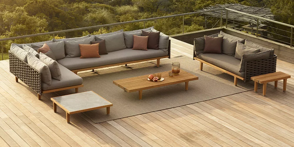 Dedon Loungesofa Sealine auf einer Terrasse mit Holzboden und Wald im Hintergrund