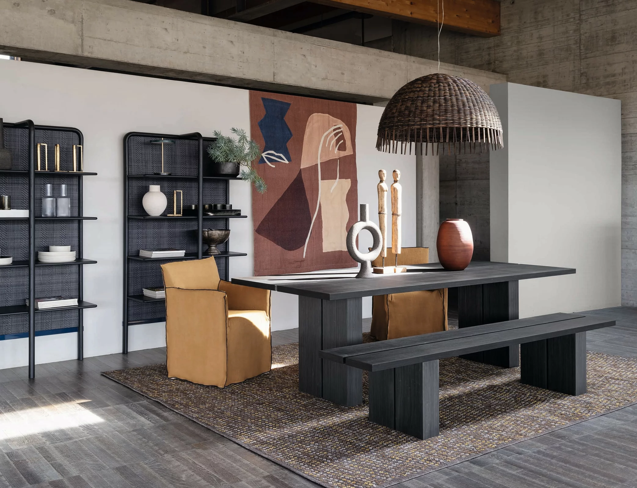 Esszimmer mit Gervasoni Tisch und Bank aus dunklem Holz zwei braunen Stühlen und dekorativen Elementen auf einem Teppich in einem modernen Raum