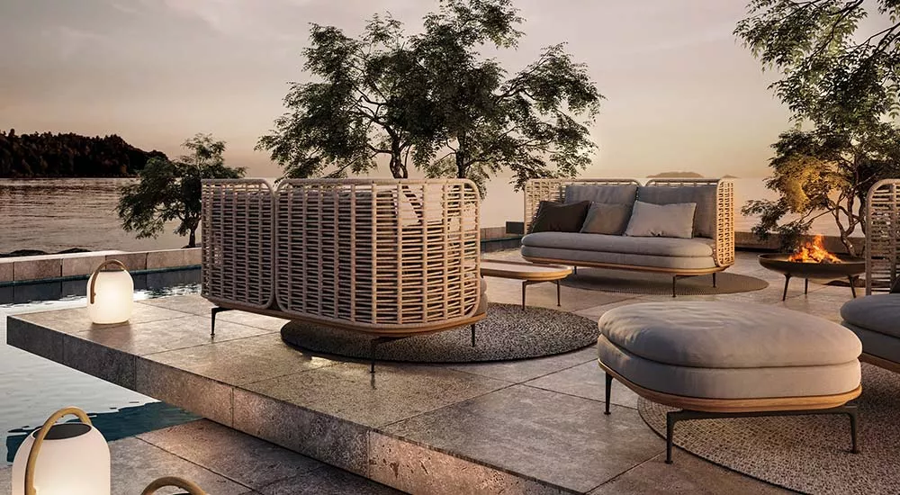 Gloster Mistral Gartenmöbel Loungegruppe in Naturtönen auf einer Terrasse mit Seeblick bei Sonnenuntergang, stimmungsvolle Atmosphäre.