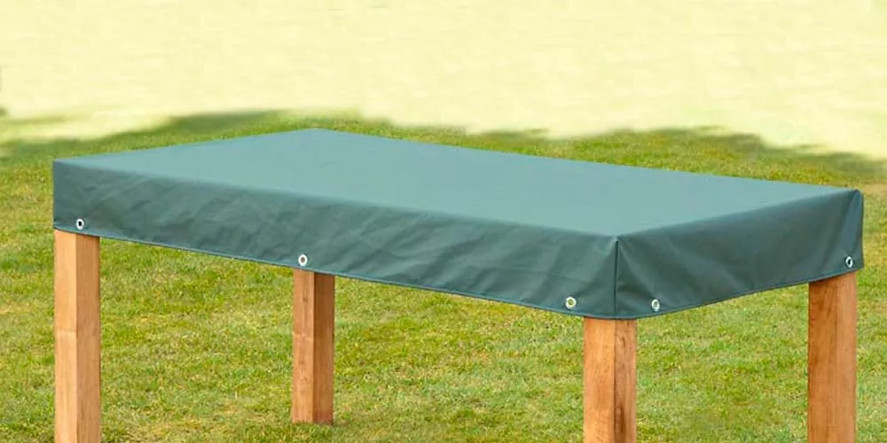 Grüne Tischhaube von Villa Schmidt, Premium Cover, auf Holztisch im Garten, technische Stoffansicht.