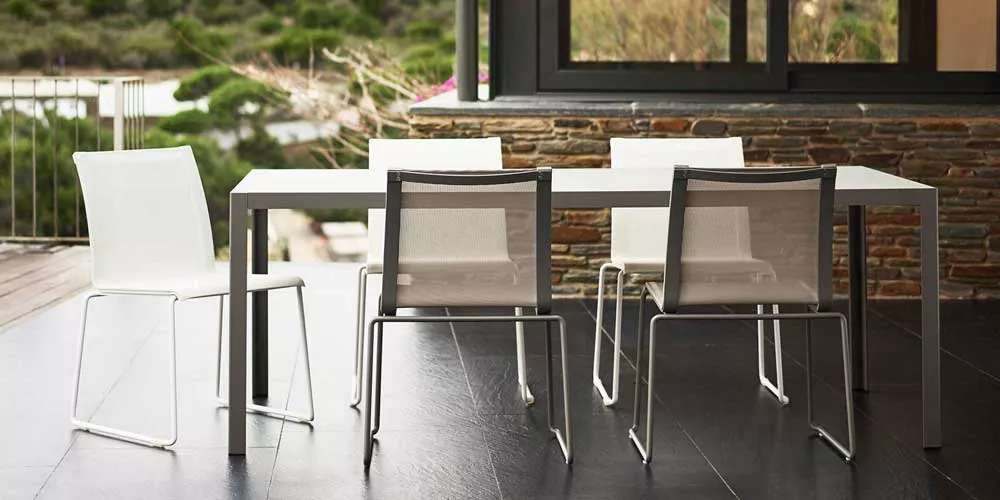 Bivaq Club Essgruppe in Weiß auf einer Terrasse mit modernem Hintergrund, bestehend aus einem Tisch und vier Stühlen, ideal für den Garten.