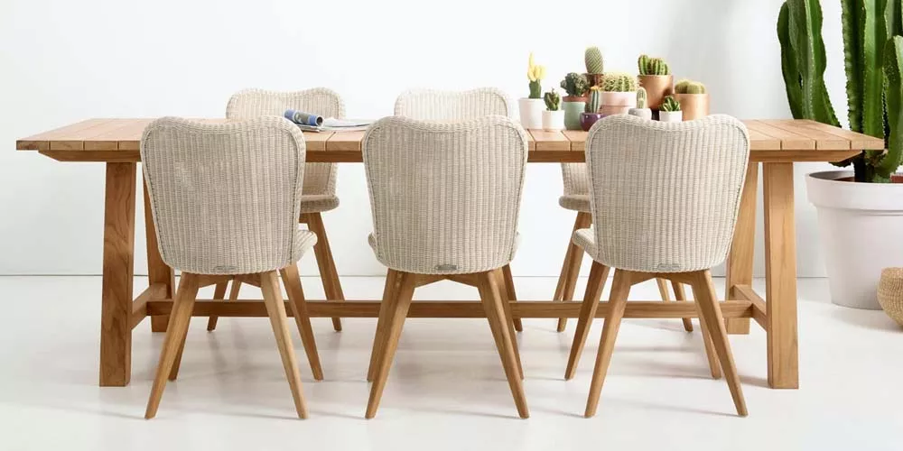 Sechs Vincent Sheppard Lena Stühle in Creme vor einem Holztisch, umgeben von Kakteen auf hellem Hintergrund, als Mood-Bild.