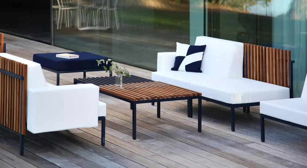 EGO Paris Sutra Essgruppe in Weiß und Holzoptik auf einer modernen Terrasse mit Glaswand im Hintergrund, stimmungsvolle Außenaufnahme.