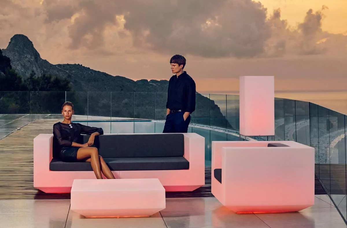 Vondom Vela Loungegruppe in Weiß und Schwarz auf einer Terrasse mit Meerblick bei Sonnenuntergang, moderne Gartenmöbel in stilvollem Design.