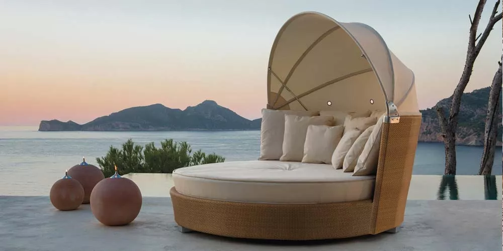 POINT Romantic Outdoor Loungegruppe in Beige auf einer Terrasse mit Meerblick und Insel im Hintergrund, stimmungsvolle Abenddämmerung.