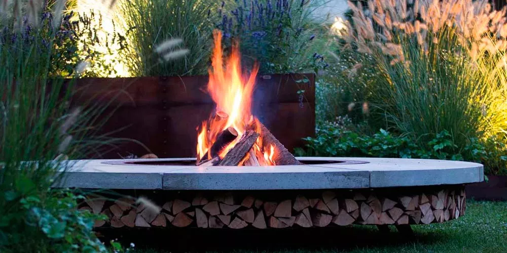 Ak-47 Feuerstellen Ercole im Garten mit brennendem Feuer umgeben von Pflanzen und Gräsern stimmungsvolles Bild