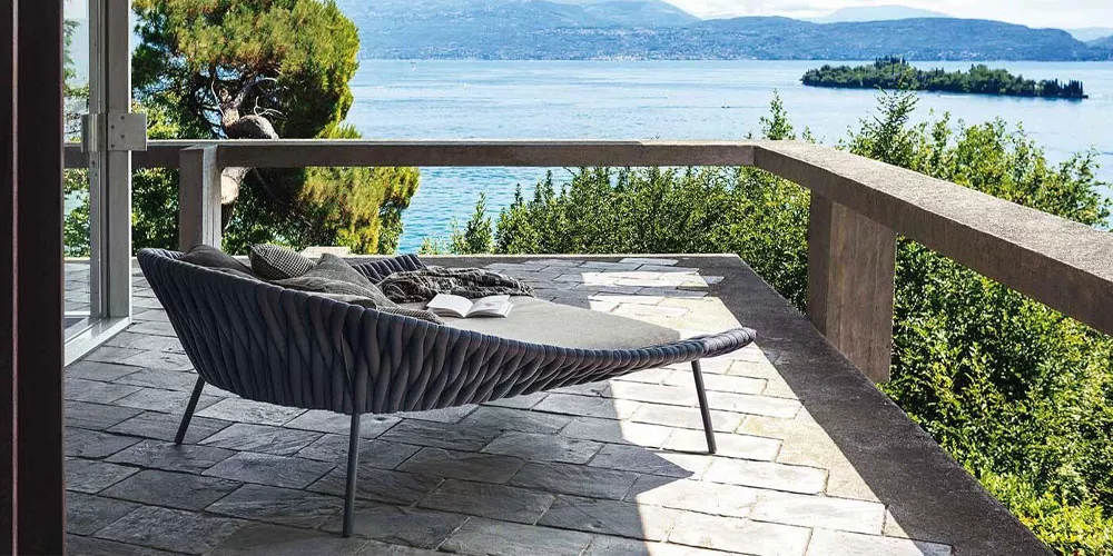 Roda Kollektion Arena in Grau auf einer Terrasse mit Seeblick, umgeben von Bäumen und Bergen, entspannte Atmosphäre.