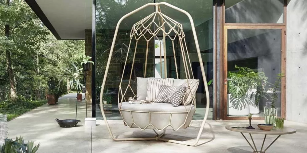 Gartenmöbel von Roberti Gravity in Beige, abgebildet auf einer Terrasse mit Glasfront und Pflanzen im Hintergrund.