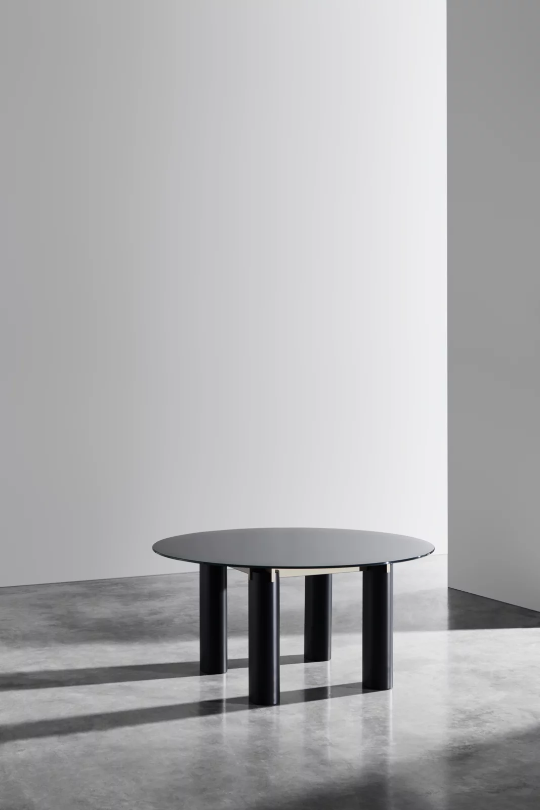 Gervasoni Tisch 3013 in Schwarz mit runder Glasplatte und vier Beinen in einem minimalistischen Raum ohne Hintergrund