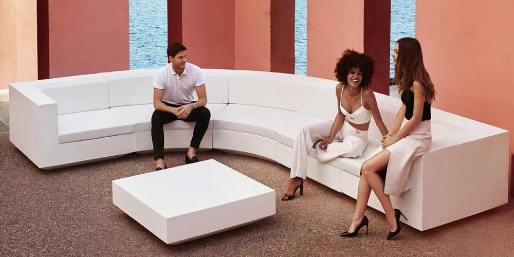 Drei Personen sitzen auf der weißen Vondom Vela Loungegruppe im Freien vor einem Hintergrund mit Meerblick.