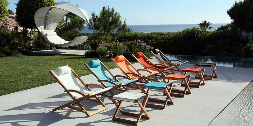 Royal Botania Beacher Loungegruppe in verschiedenen Farben auf einer Terrasse mit Meerblick und Garten im Hintergrund.