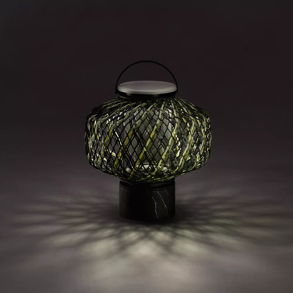 Dedon The Others Gartenleuchte Laterne in einem dunklen Raum mit eingeschaltetem Licht das ein Muster auf den Boden wirft