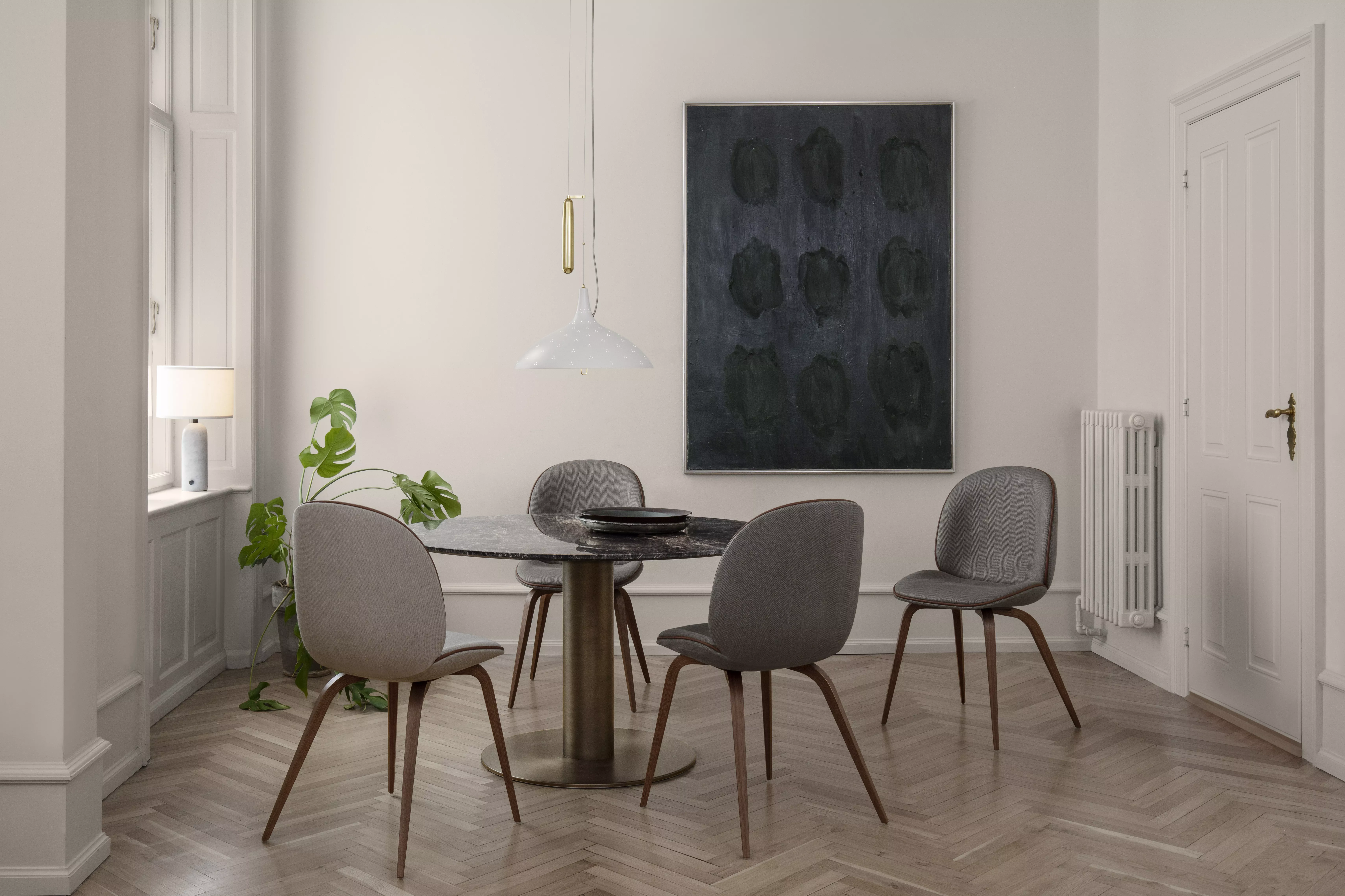 Ein stilvoll eingerichtetes Esszimmer mit Gubi Beetle Dining Chairs einem Gubi 2-0 Dining Table einer Gravity Table Lamp Small und einer A1965 Pendant.