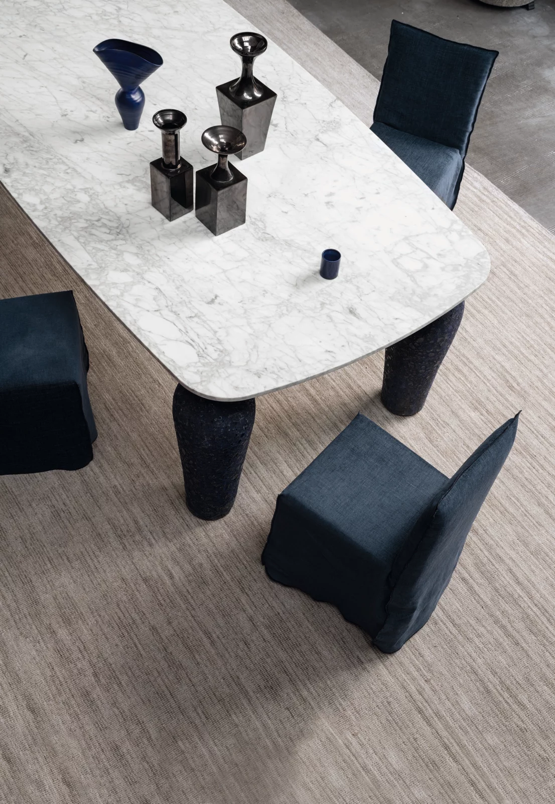 Gervasoni Tisch mit Marmorplatte und blauen Stühlen auf einem Teppich in einem modernen Esszimmer.