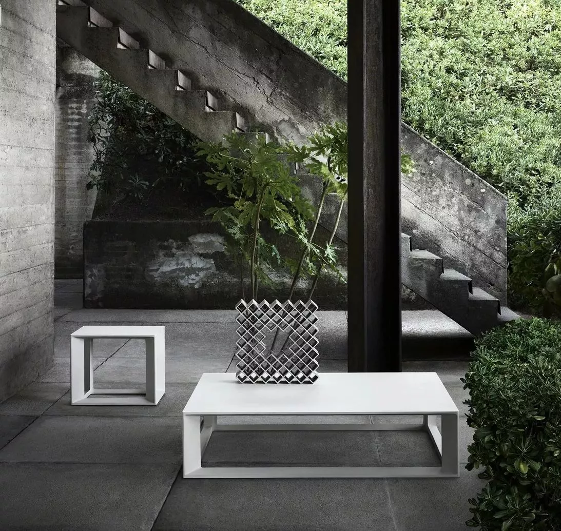 B&B Italia Pablo Outdoor Loungetische in einem modernen Garten mit Betonstufen und grüner Vegetation im Hintergrund