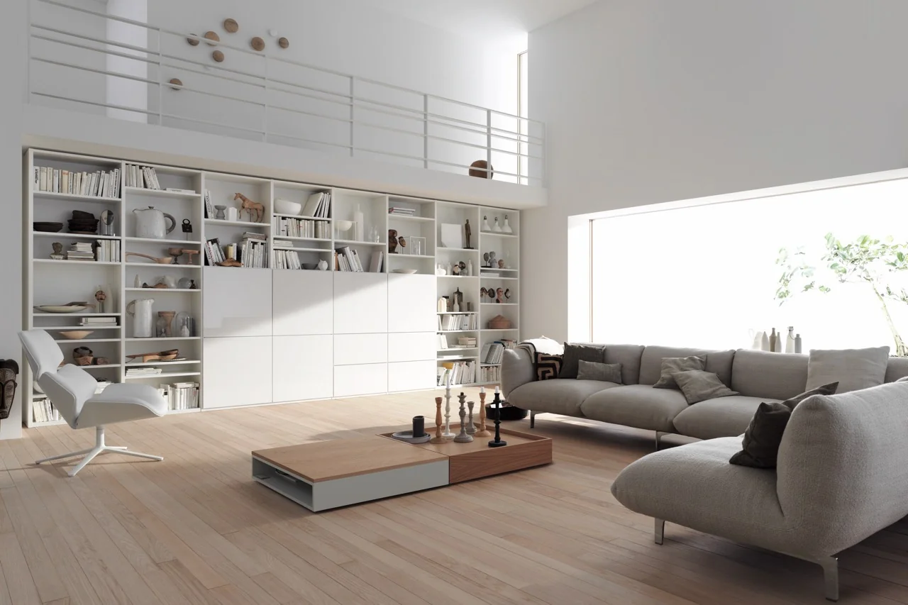 Helles Wohnzimmer mit Interlübke Studimo Regal in Weiß, gefüllt mit Büchern und Dekorationen, neben grauem Sofa und modernem Sessel.