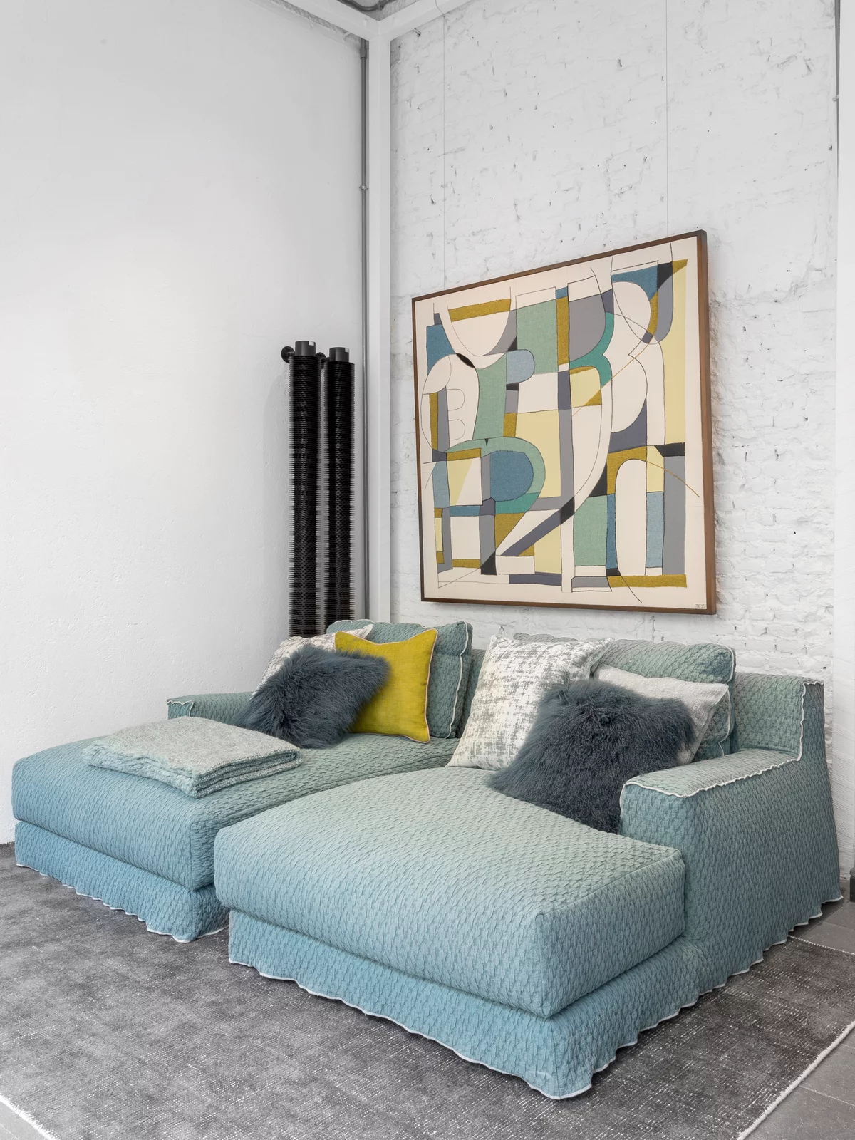 Zwei blaue Gervasoni Sofas mit Kissen und Decken in einem modernen Wohnzimmer mit abstraktem Kunstwerk an der Wand