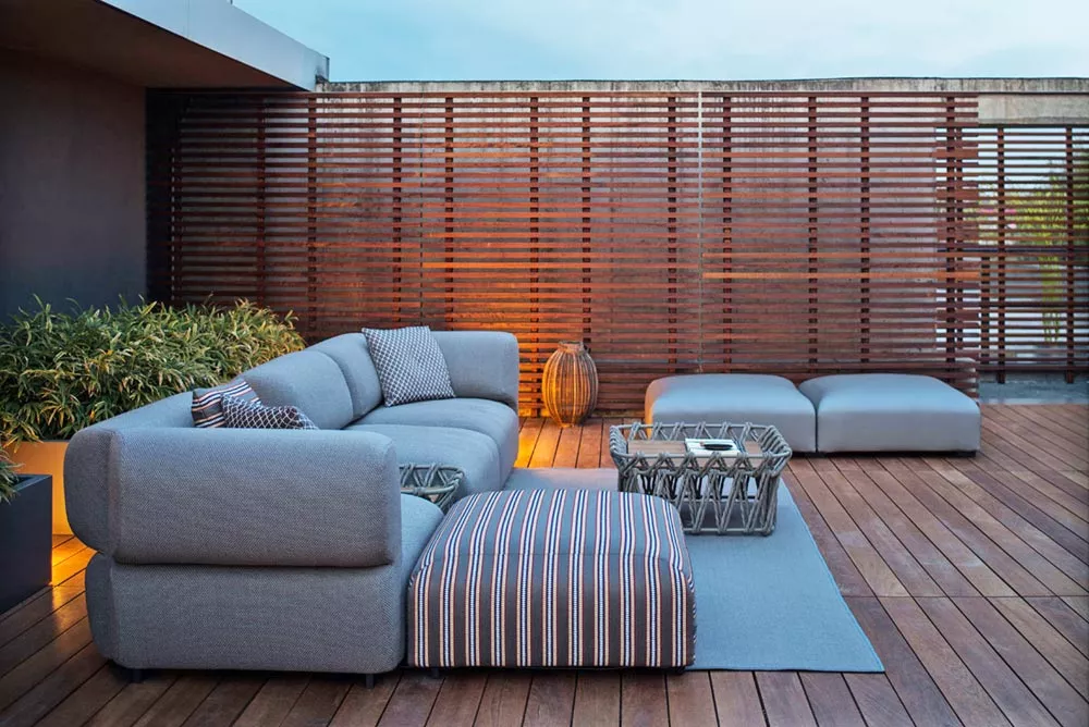 B&B Italia Butterfly Gartenmöbel Loungegruppe auf einer modernen Terrasse mit Holzboden und Pflanzen im Hintergrund bei Sonnenuntergang.