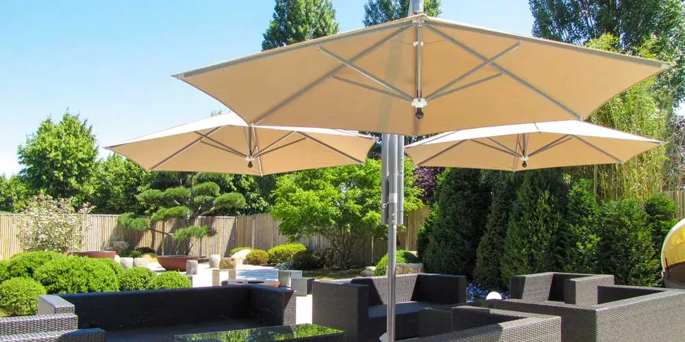 May Sonnenschirme Rialto in Beige auf einer modernen Terrasse mit grüner Gartenlandschaft im Hintergrund.