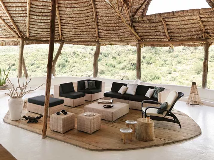 Dedon Lounge hochwertige Gartenmöbel in einer gemütlichen Outdoor-Szene mit Blick auf die Natur unter einem Strohdach.