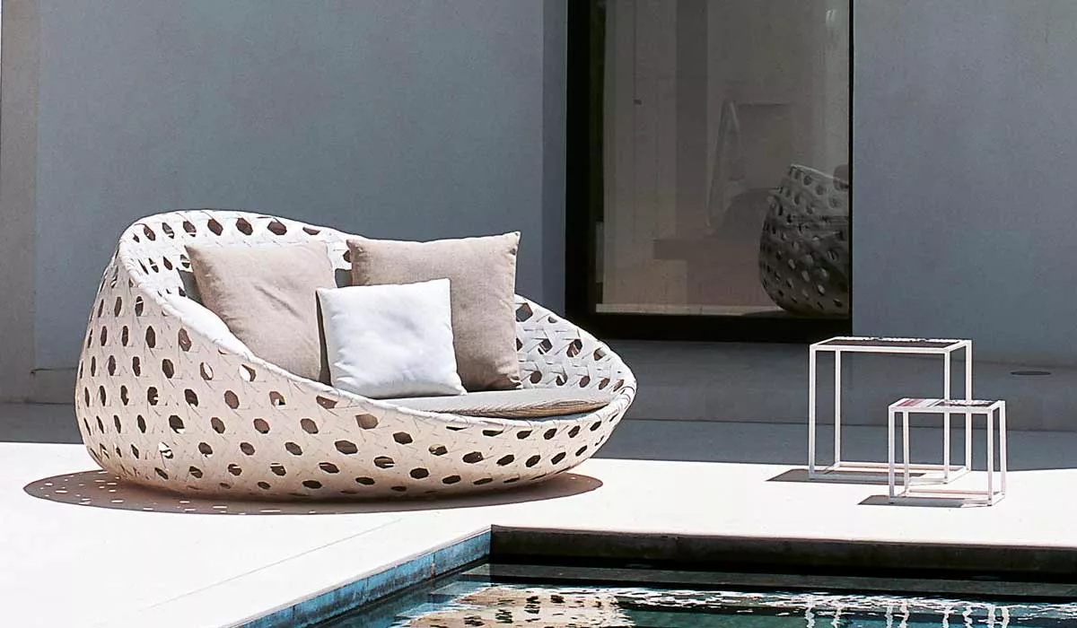 BeB Italia Canasta Loungesofa steht auf einer Terrasse neben einem Pool mit zwei kleinen Beistelltischen im Freien.