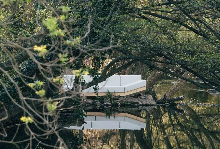Calma Alat Wood Loungesofa in Weiß, 350 cm, auf einer Insel inmitten eines ruhigen, bewaldeten Flussufers platziert.