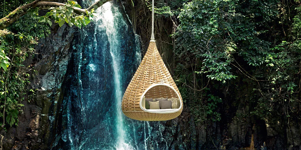 Dedon Nestrest Hängesessel hängt vor einem Wasserfall in einem dichten Wald und bietet eine entspannende Rückzugsmöglichkeit in der Natur
