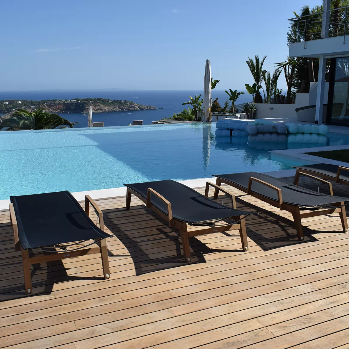 Sonnenliege Muse von Royal Mirage in Schwarz auf Holzterrasse mit Meerblick im Hintergrund.