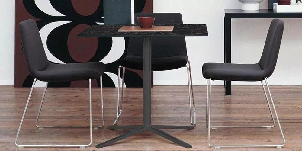 Drei BeB Italia Cosmos Stühle und ein Tisch in einem modernen Esszimmer mit Holzboden und stilvoller Dekoration im Hintergrund.