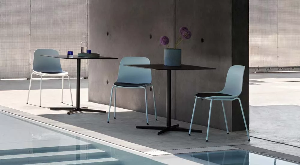 Lapalma AUKI Outdoor Essgruppe in Blau und Schwarz, bestehend aus zwei Tischen und vier Stühlen, auf einer Terrasse am Pool.