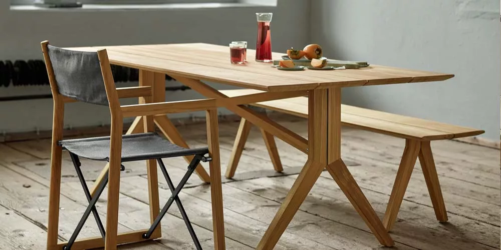 Weißhäupl Loft Tisch und Bank aus hellem Holz mit schwarzem Klappstuhl auf Holzboden in modernem, lichtdurchflutetem Raum.