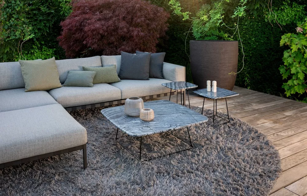 Draenert Manolo Couchtische in einem gemütlichen Gartenambiente mit grauem Teppich und modernen Gartenmöbeln auf einer Holzterrasse