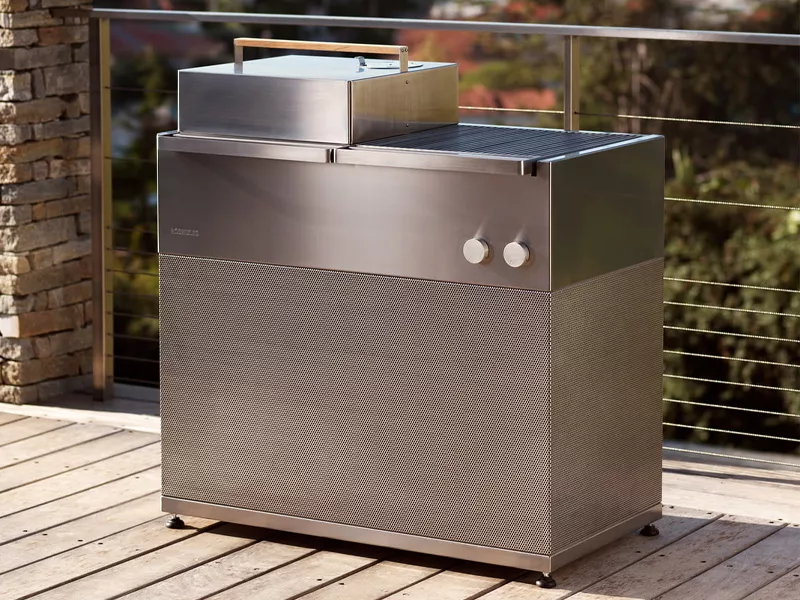 Röshults BBQ in Edelstahl auf einer Holzterrasse mit modernem Hintergrund, ideal für stilvolle Outdoor-Kochabende.