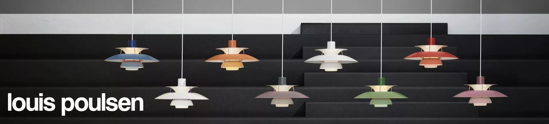 Acht Louis Poulsen PH5 Pendelleuchten in verschiedenen Farben hängen vor einer grauen Treppe.