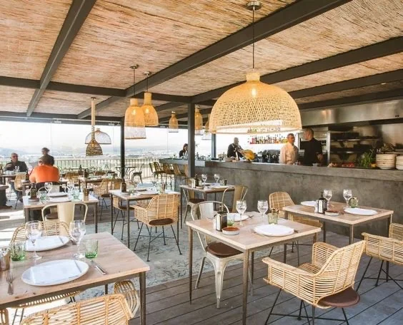 Gemütliche Restaurantterrasse mit Bambusmöbeln und großen, geflochtenen Lampen, die eine warme, einladende Atmosphäre schaffen.