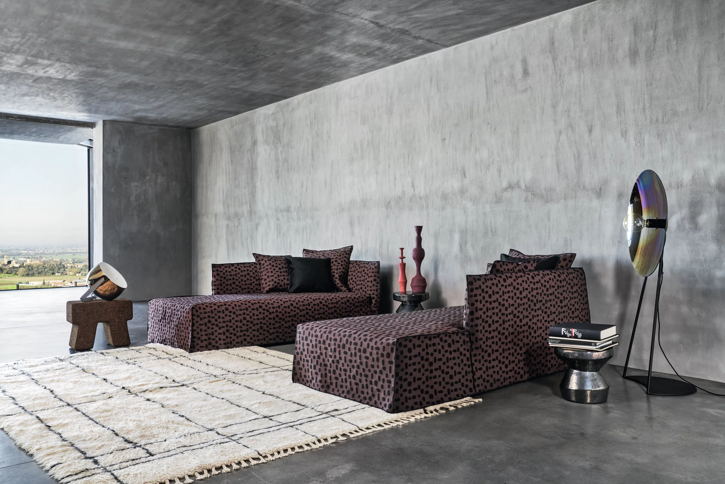 Wohnzimmer mit Gervasoni Ghost Sofa in dunkelbraunem Stoff, moderne Dekoration und Betonwänden, stimmungsvolles Ambiente.