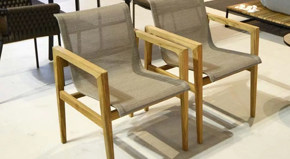 Zwei fischer möbel Barcelona Essstühle aus hellem Holz und grauem Stoff auf hellem Boden in moderner Ausstellungsumgebung.