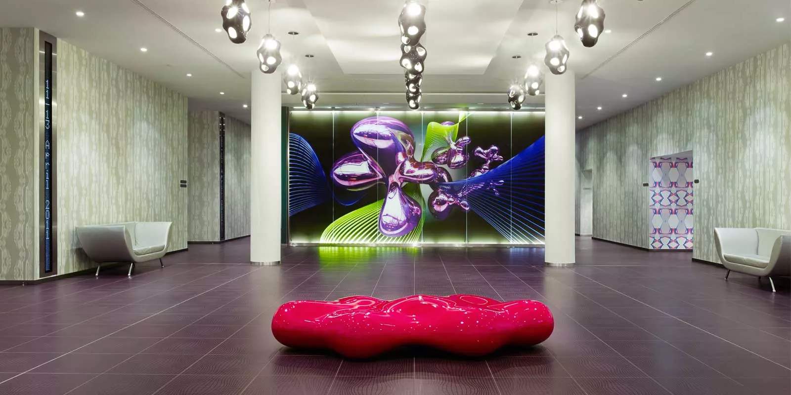 Rote Vondom Lava Bank von Karim Rashid in modernem Foyer mit futuristischem Wanddesign, ideal für stilvolle Außenbereiche.